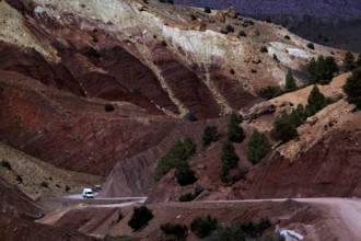 Dramatic red rocks and vehicles on snaking roads in Assaka Gorge