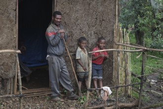 Man with two children in front of a traditional house along the route from Yirga Alem to Yabello,