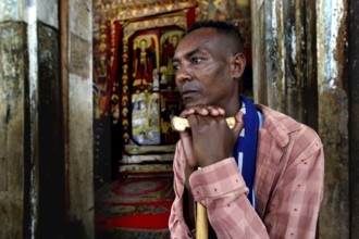 Believer is leaning on a stick at Ura Kidhane Mihret Church on Lake Tana, Lake Tana, Ethiopia
