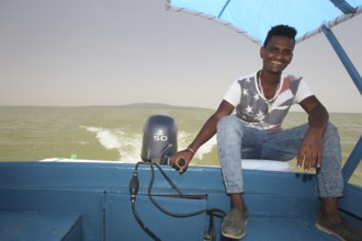 Captain rides a motor boat on Lake Tana under a blue sky, Lake Tana, Ethiopia