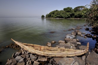 Papyrus boat is lying on a rocky shore with a view of Lake Tana, zero