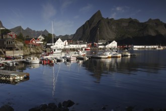 Sakrisøy harbour, where boats lie in calm water against a majestic mountain backdrop, Sakrisøy,