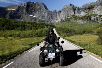 Person riding on ATV on a picturesque road in Flakstadøy, Flakstadøy, Lofoten, Norway