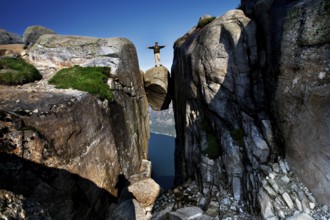 Daring person standing on the impressive Kjeragbolten above the fjord, Lysefjord, Norway