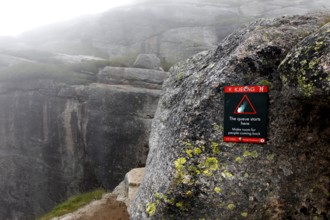 Warning on rock against the backdrop of the misty Kjerag landscape, Lysefjord, Rogaland, Norway