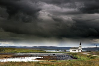 Small church in Nesseby under thick, dramatic clouds in the sky, Nesseby, Finnmark, Norway