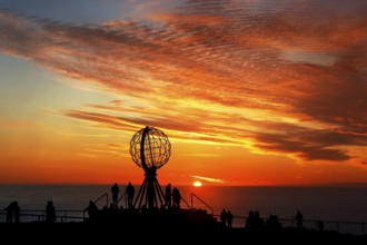 Sunset on the North Cape with colorful clouds and silhouettes in front of the globe, North Cape,