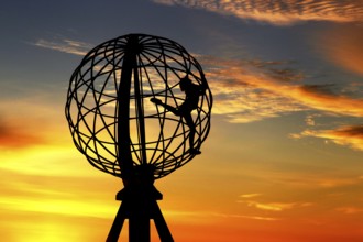 Silhouette of a climber on the North Cape globe in front of a colorful sunset, North Cape,