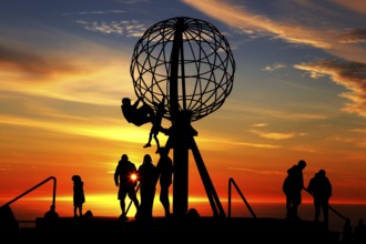 Silhouettes of people on the North Cape globe in front of a glowing sunset, North Cape, Magerøya,