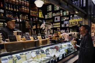 Sales stand with diverse delicacies and interacting customers at Queen Victoria Market, Melbourne,