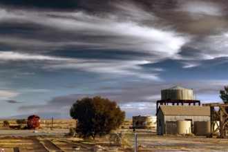 Industrial building with water tower in rural Marree under dramatic sky, Marree, South Australia,