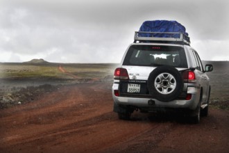 A Landcruiser drives along a track on the Sanetti Plateau under overcast skies, Bale Mountains,