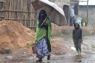 Woman and child under umbrella during rain in Rira, Bale Mountains, Rira, Bale Mountains, Ethiopia