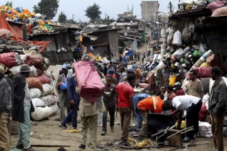 People carry large bags on their shoulders through the bustling Mercato in Addis Ababa, Addis