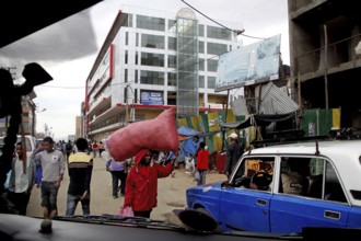 Busy street scene with passers-by and cars in front of modern buildings, Addis Ababa, Mercato,