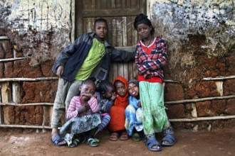Children in colorful clothes pose happily in front of a traditional house, Dorze village, Ethiopia