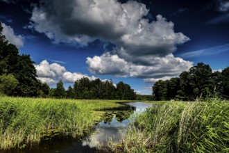 Lush landscape with river and impressive cloud formations in Ginuciai