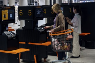 Customers use self-service checkouts with shopping trolleys in the shopping center, Tallinn, South