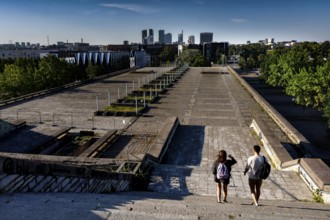 Two walkers on the abandoned platform of the city hall (Linnahall) with skyline view, Tallinn,
