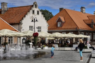 Lively scene in front of the historic Weighouse with people and fountains, Kuressaare, Saaremaa,