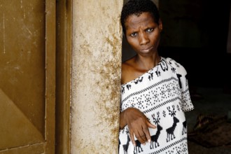 A woman wearing black and white clothes is leaning thoughtfully at a door, Bouké, region, Côte