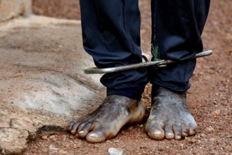 Cuffed feet in sandy surroundings illustrate mental distress, Korhogo, Ivory Coast