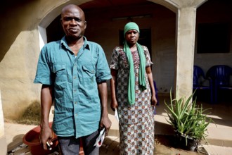 A man and a woman stand in front of their house, radiating strength together, Korhogo, CI, West