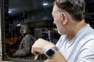 Two men in a Lebanese restaurant, one looking at the other through the window, Korhogo, CI, West