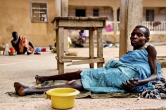A woman lies relaxed on the ground surrounded by everyday objects, Bouké, region, Côte d'Ivoire