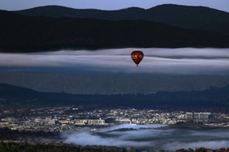 View of Canberra from Mount Ainslie Lookout with a hot air balloon against a mountainous backdrop,
