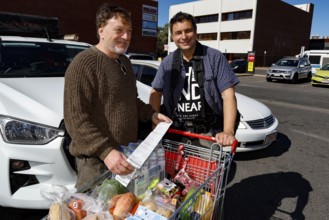 Two men shopping in front of a Coles supermarket in a happy mood, Alice Springs, Northern