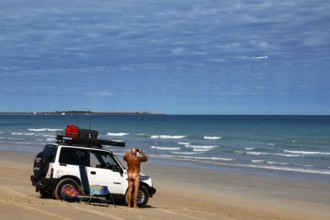 Jeep parked on a wide sandy beach with ocean views in sunny weather, Broome, Western Australia,