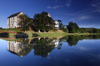 Kastelholm Castle in Åland with reflection in a quiet lake and wooded shoreline landscape, zero