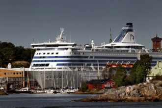 Island in Helsinki with traditional wooden house and large ferry in the background, Helsinki,