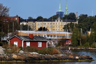 Red wooden house on a Helsinki island surrounded by water and lush greenery, Helsinki, Finland