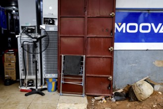 A locked door in an urban environment surrounded by dirt and scattered objects, Bouaké, Côte