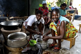 Women cooking smiling in a simple kitchen with kitchenware and pots, Bouaké, null, Côte d'Ivoire