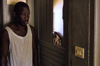 Thoughtful man standing in the shade of a door in a simple room, Bouake, null, Côte d'Ivoire