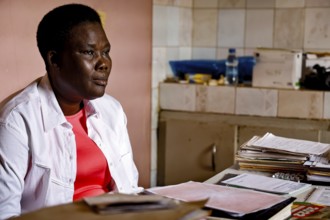 Nurse sitting seriously at desk surrounded by files and documents, Bouké, region, Côte d'Ivoire