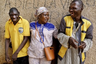 Two men interacting warmly with a nurse in front of a wall in Bouaké, Bouaké, Saint Camille, Nimbo,