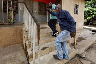 Nurse Albert helps a patient climb stairs, Bouaké, Nimbo, Côte d'Ivoire