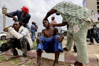 A group cares for a mentally ill homeless person on the street in Bouaké, Bouaké, Côte d'Ivoire