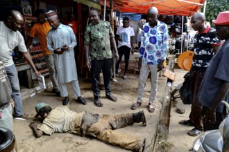 Homeless person receives care on the street, surrounded by helping people, CI Bouaké, Ivory Coast