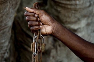 A hand firmly holds a heavy chain as a symbol of suffering, Bouaké, Ivory Coast