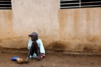 A patient sits alone with a plate against a wall, Bouaké, Nimbo, Côte d'Ivoire