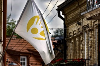 White flag with yellow symbol flying in Uzupis, Vilnius under cloudy sky, Vilnius, Vilnius County,