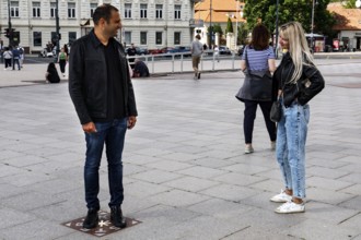 A couple talking on the miracle tile on Cathedral Square in Vilnius, Vilnius, Vilnius County,