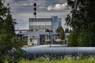 Abandoned power plant with large buildings and chimney surrounded by trees, Visaginas, Lithuania