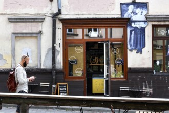 Passerby walks past a cafe in Uzupis, Vilnius, mural in the background, Vilnius, Vilnius County,