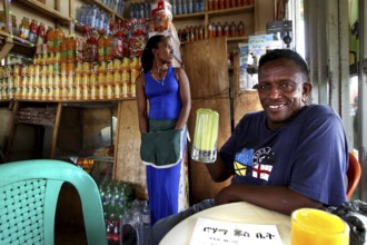Man holding drink in colorful juice bar in Bahirdar, cheerful atmosphere, Bahirdar, Ethiopia